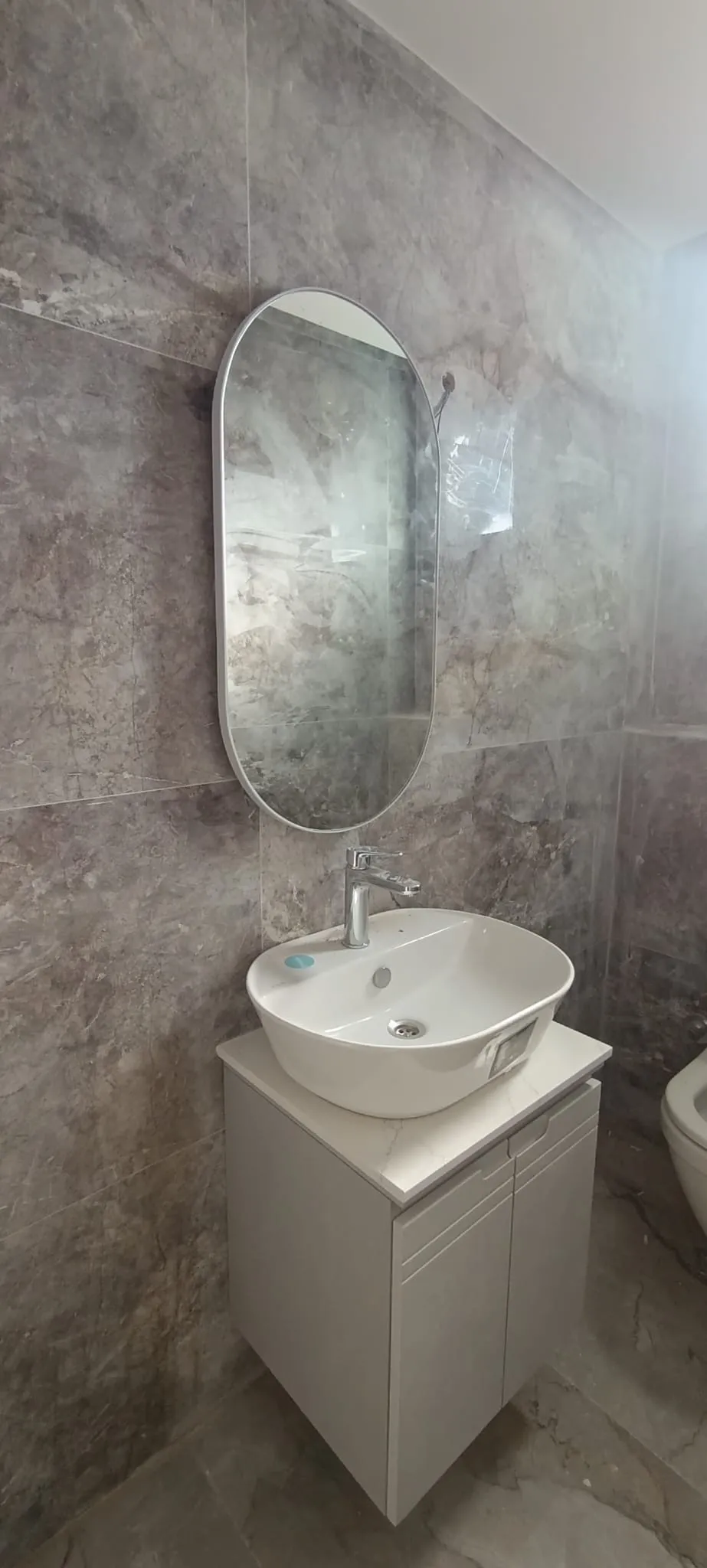 Gri mermer banyo, çanak lavabo ve oval ayna