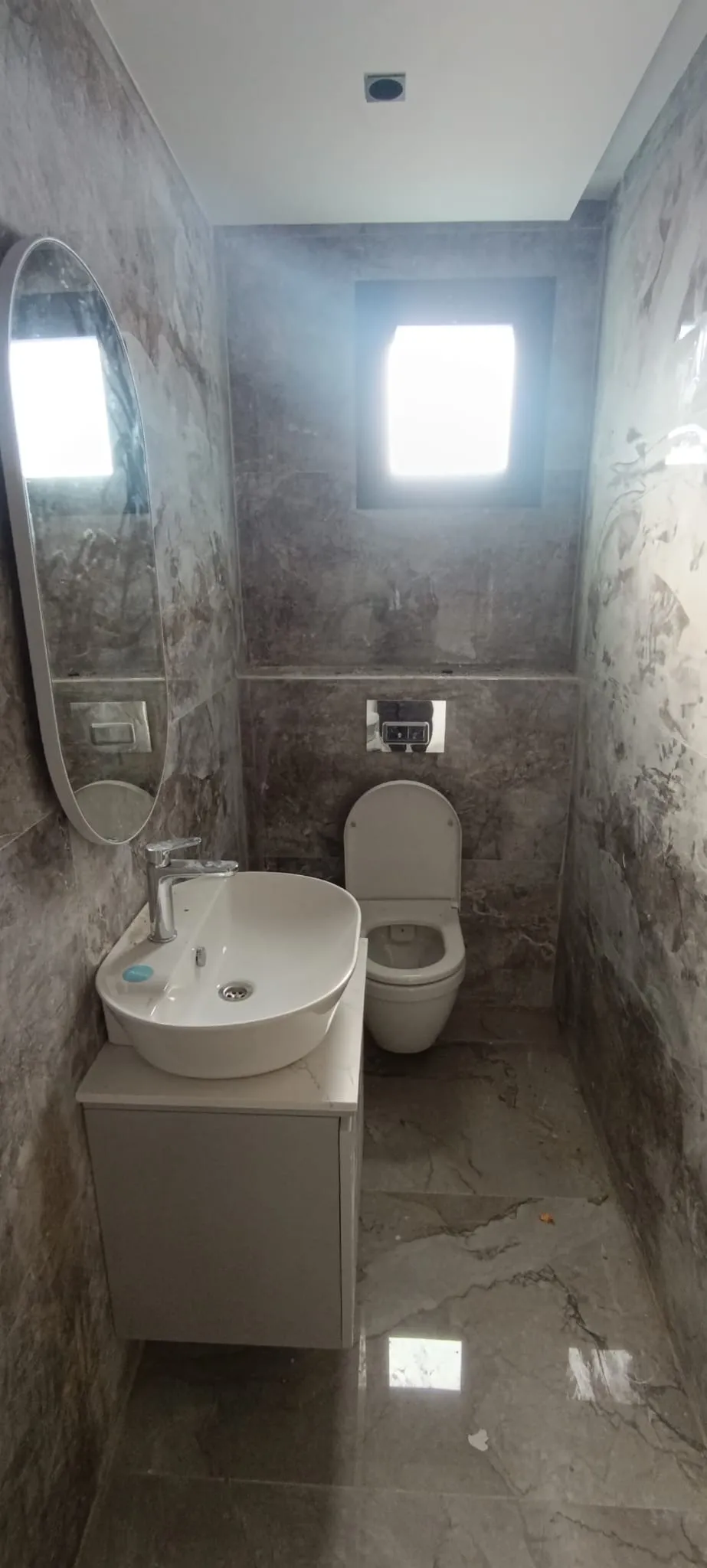 Gri mermer banyo, oval ayna ve çanak lavabo